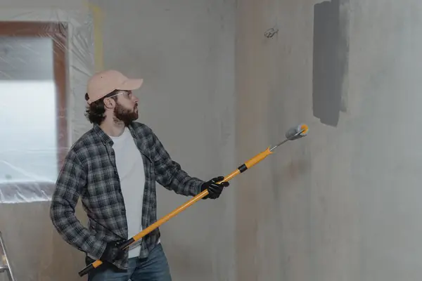 Painter rolling grey paint onto an interior wall in Dayton